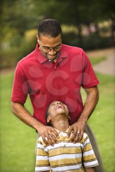 Royalty Free Photo of a Father Standing Behind His Son With Hands on His Shoulders