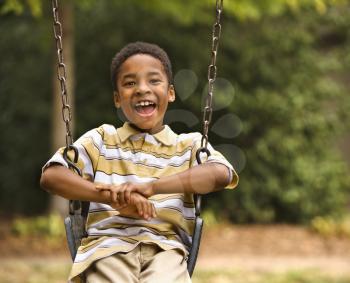 Royalty Free Photo of a Happy Boy Playing on a Swing