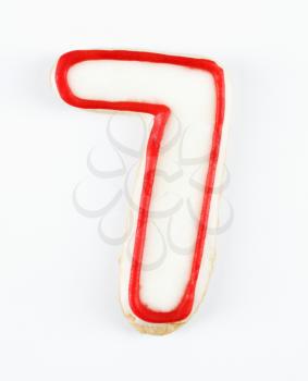 Sugar cookie in the shape of a number seven outlined in red icing.