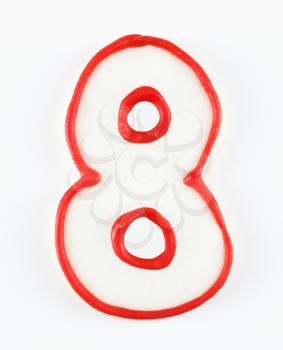 Sugar cookie in the shape of a number eight outlined in red icing.