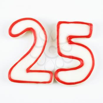 Sugar cookies in the shape of the number twenty five outlined in red icing.