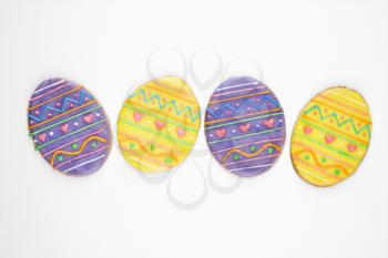 Four sugar cookies in shape of Easter eggs with decorative icing.