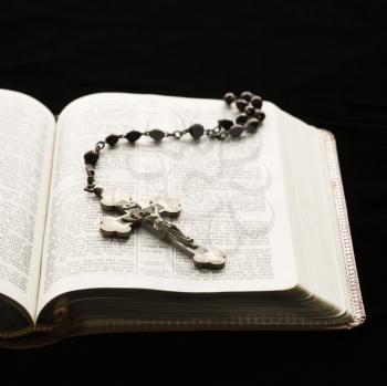 Royalty Free Photo of a Crucifix on a Rosary Lying on an Open Bible