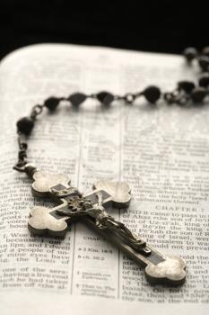 Royalty Free Photo of a Crucifix on a Rosary Lying on an Open Bible