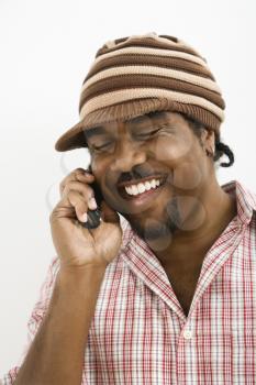 Royalty Free Photo of a Man Wearing a Hat and Smiling While Talking on a Cellphone