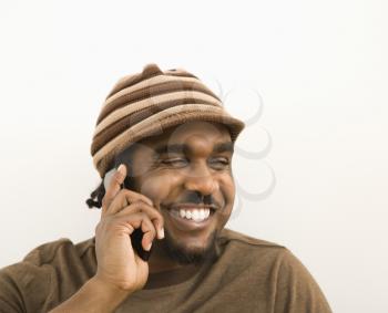 Royalty Free Photo of a Man Wearing a Hat and Smiling While Talking on a Cellphone
