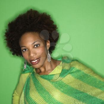 Portrait of woman with afro wearing green striped shawl on green background smiling.