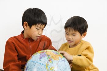 Royalty Free Photo of Two Boys Pointing at a World Globe and Smiling