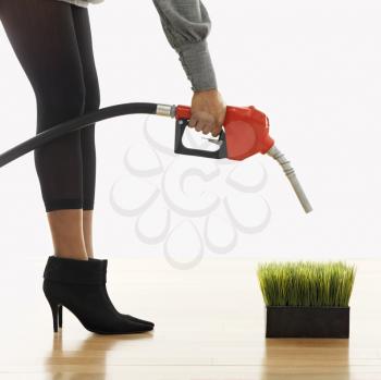 Royalty Free Photo of a Woman holding gasoline pump nozzle over green grass