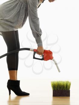 Royalty Free Photo of a Woman Holding a Gasoline Pump Nozzle Over Green Grass