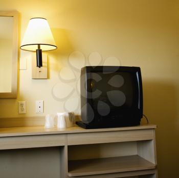 Royalty Free Photo of an Interior Shot of a Motel Room With a TV Set on a Nightstand Next to a Wall Lamp
