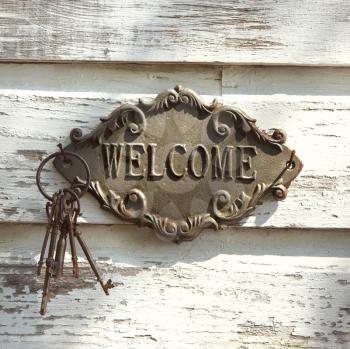 Royalty Free Photo of a Welcome Sign and Metal Keys on an Old White Peeling Building