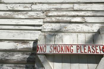 Royalty Free Photo of a Sign on an Old White Peeling Building Reading No Smoking Please