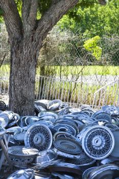 Royalty Free Photo of a Pile of Old Hubcaps Next to a Tree