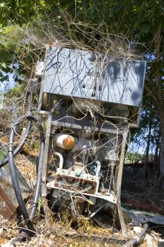 Royalty Free Photo of an Old Broken Gasoline Pump Covered With Weeds