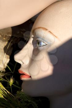 Closeup of face of mannequin on ground.