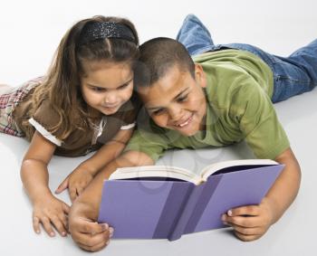 Royalty Free Photo of a Brother and Sister Reading a Book Together Sitting on the Floor