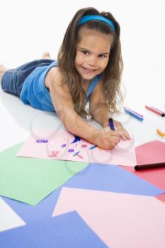 Royalty Free Photo of a Girl Coloring on Construction Paper and Smiling