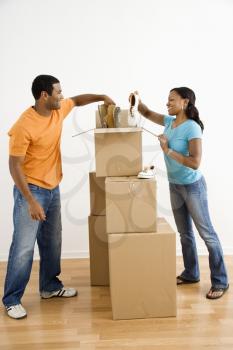 African American male and female couple packing cardboard boxes with shoes.