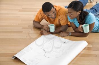 Royalty Free Photo of a Couple Looking at Architectural Blueprints and Holding Coffee Cups