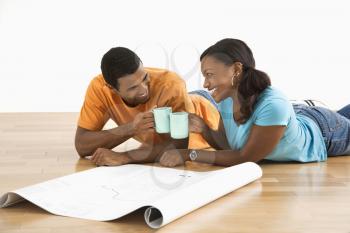 Royalty Free Photo of a Couple With Architectural Blueprints Toasting With Their Coffee Cups