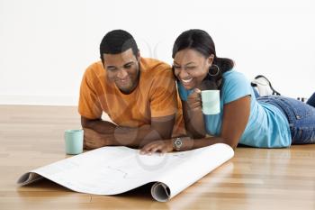 Royalty Free Photo of a Couple Lying on the Floor With Architectural Blueprints