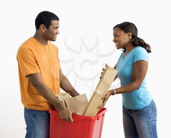 Royalty Free Photo of a Man Holding a Recycling Bin While a Pretty Woman Puts Cardboard In