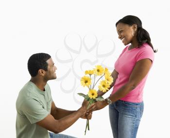 Royalty Free Photo of a Man on His Knees Giving a Woman a Bouquet of Flowers