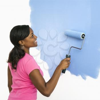 Royalty Free Photo of a Woman Painting a Wall Blue and Smiling