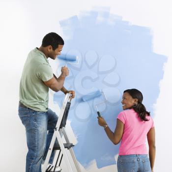 Royalty Free Photo of a Couple Painting a Wall Blue and Smiling at Each Other