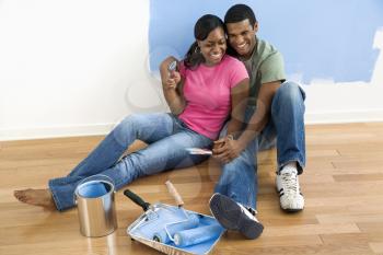 Royalty Free Photo of an African American Couple Sitting and Relaxing By a Half Painted Wall