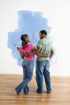 Royalty Free Photo of a Couple Standing Together Looking at a Half-Painted Wall