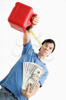 Royalty Free Photo of a Man Holding a Gas Can Pouring Gasoline Onto Money