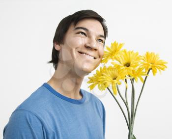 Royalty Free Photo of a Young Man Holding a Bouquet of Yellow Gerber Daisies