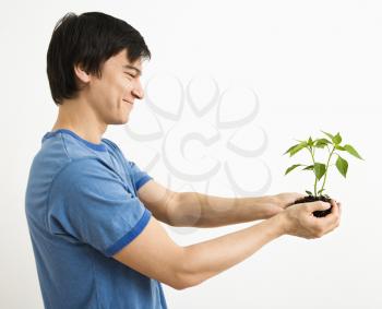 Royalty Free Photo of a Man Standing Holding a Cayenne Plant