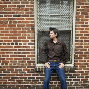 Royalty Free Photo of a Man Standing and Leaning Against a Window and Brick Wall