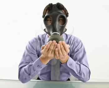 Royalty Free Photo of a Businessman Sitting wearing gas mask holding his hands over his mouth