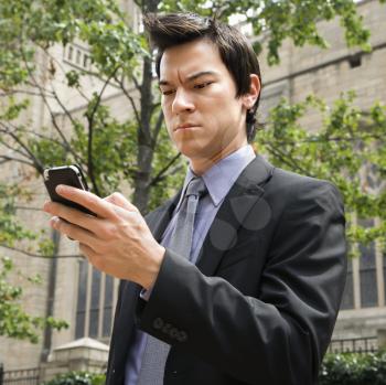 Royalty Free Photo of a Businessman Standing Looking at His Cellphone Messages