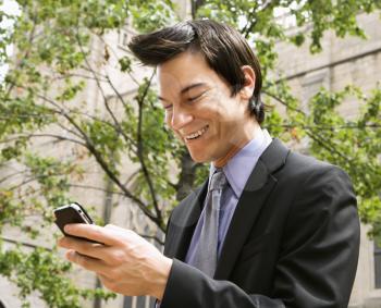 Royalty Free Photo of a Businessman Standing Looking at His Cellphone Messages