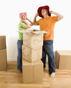 Royalty Free Photo of a Middle-aged Couple Trying on Silly Hats While Packing or Unpacking Moving Boxes