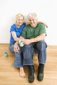 Royalty Free Photo of a Couple Sitting on the Floor Snuggling and Drinking Coffee