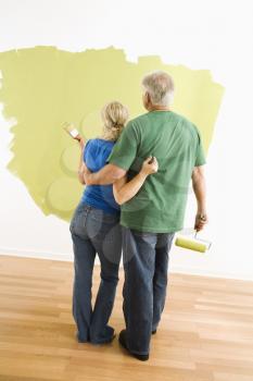 Royalty Free Photo of a Couple Painting a Wall Green and Observing Their Work
