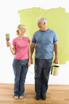 Royalty Free Photo of a Happy Couple Standing in Front of a Half-Painted Wall With Paint Supplies 'American Gothic' Style