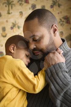 Affectionate young african-american father holds young son to his chest.  Vertical shot.