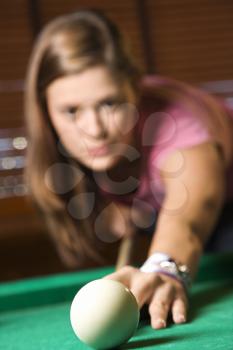 Young woman concentrating while shooting pool. Vertical shot.