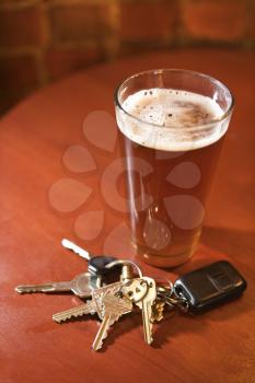 Car keys lying next to a full glass of beer.  Vertical shot.