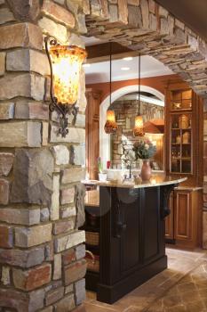 Stone archway framing dark wood cabinet with marble counter top in luxury home. Vertical shot.