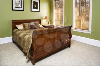 Sleigh bed in a green bedroom with wall art. Horizontal shot.