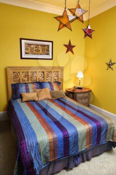 Bed with striped bedspread, decorative stars, and nightstand. Vertical shot.