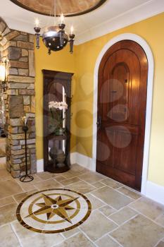 Arched front door and ceramic tile entryway of luxury home with mariner star inset. Vertical shot.